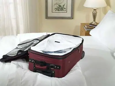 Picture of red, open suitcase on bed. The suitcase has a bed bug proof luggage liner in it.